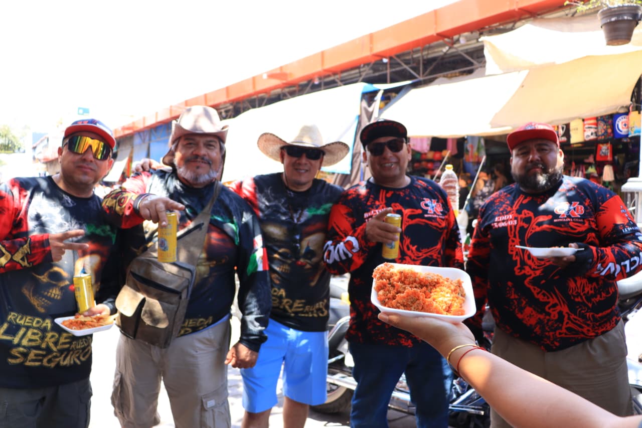 Cuatro personas motociclistas junto a un plato de ceviche de sierra