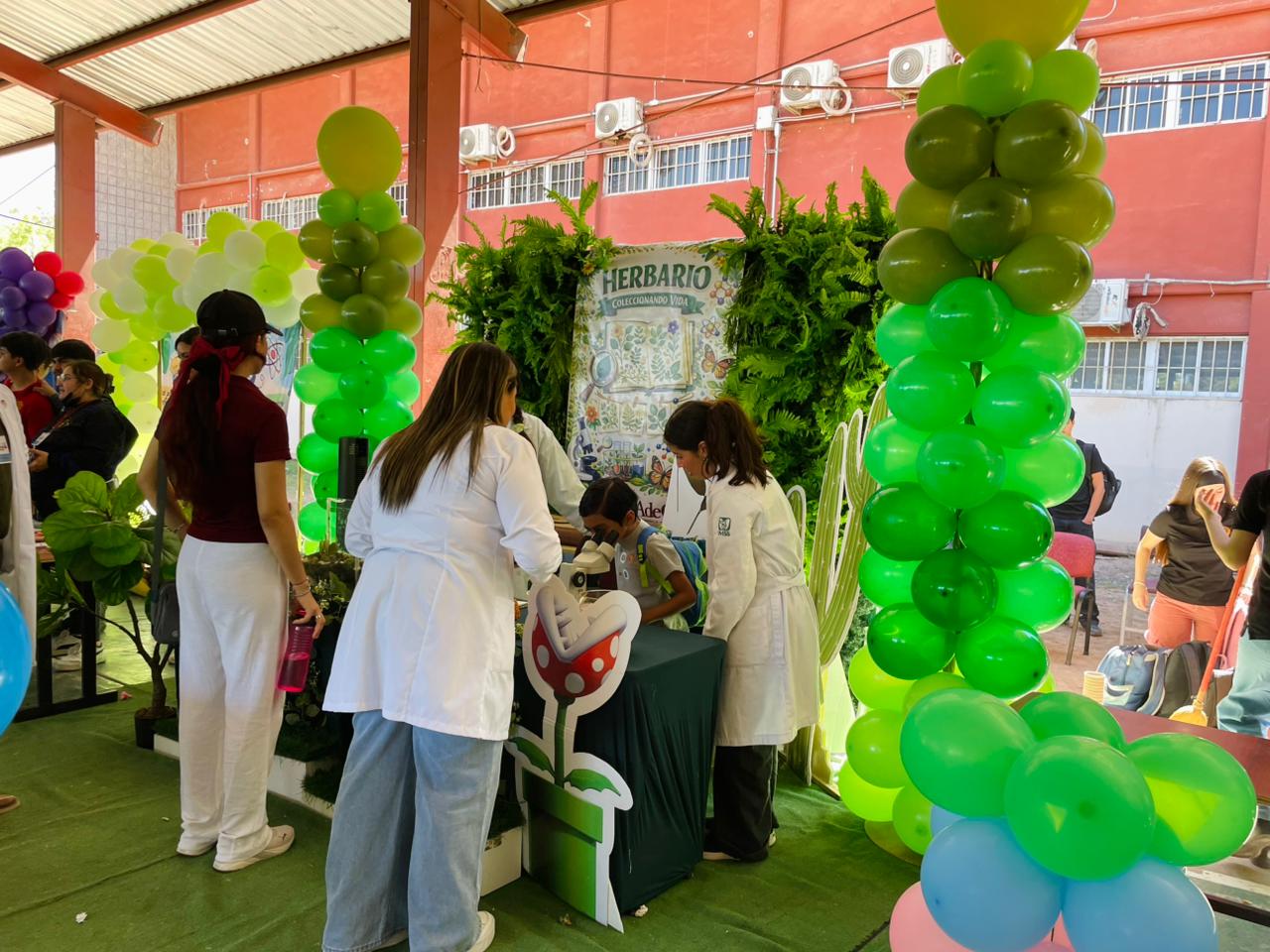 Instalaciones educativas decoradas con temática científica y maestros realizando recorrido con infantes