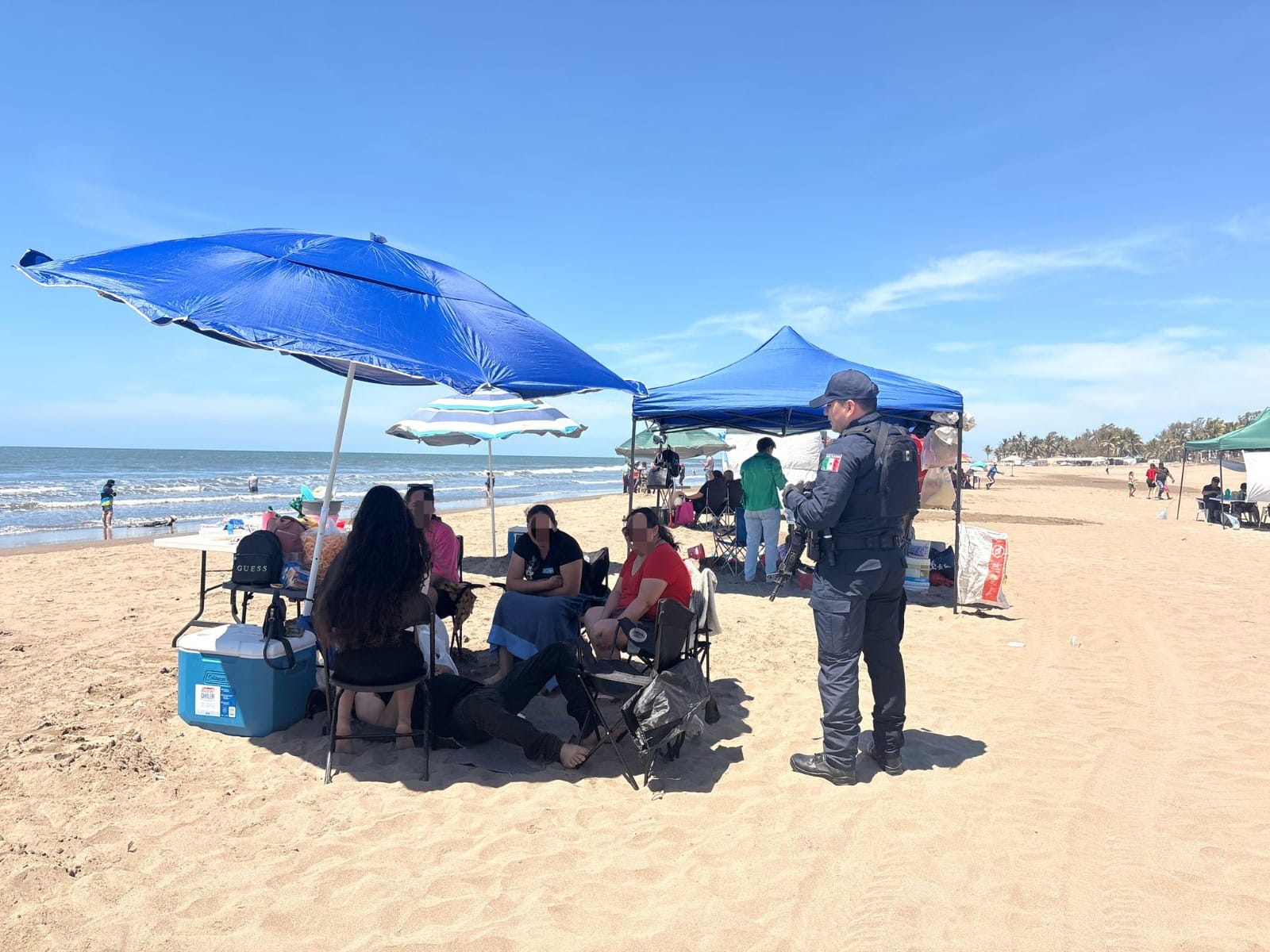 personas en la playa con sombrilla y policía
