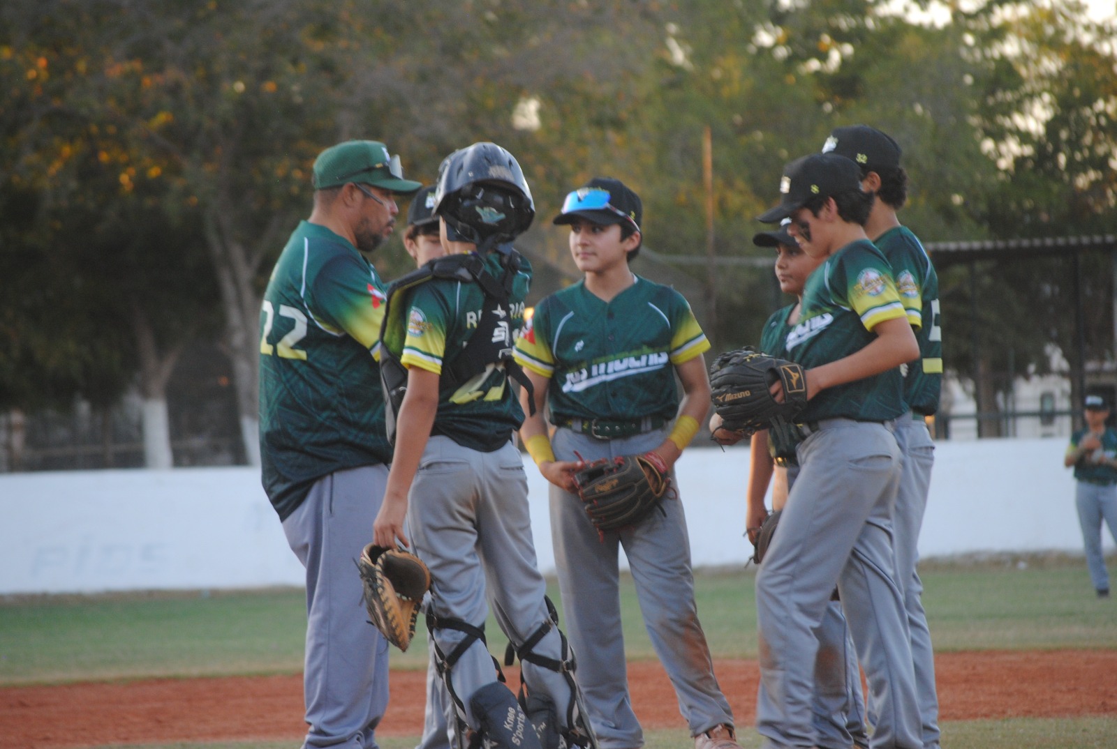 Cinco niños jugando beisbol con casaca verde