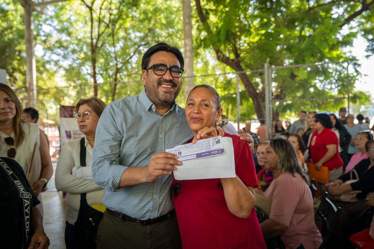 Alcalde de Culiacán junto a una mujer, haciendo entrega de un sobre