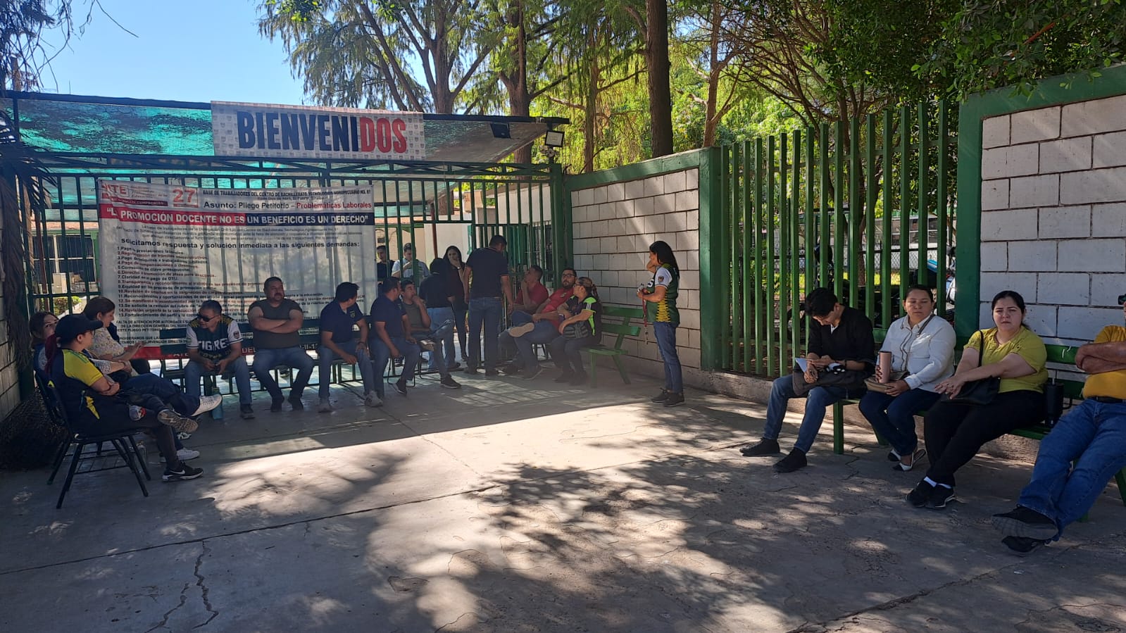 Personas sentadas a las afueras de una instalación educativa