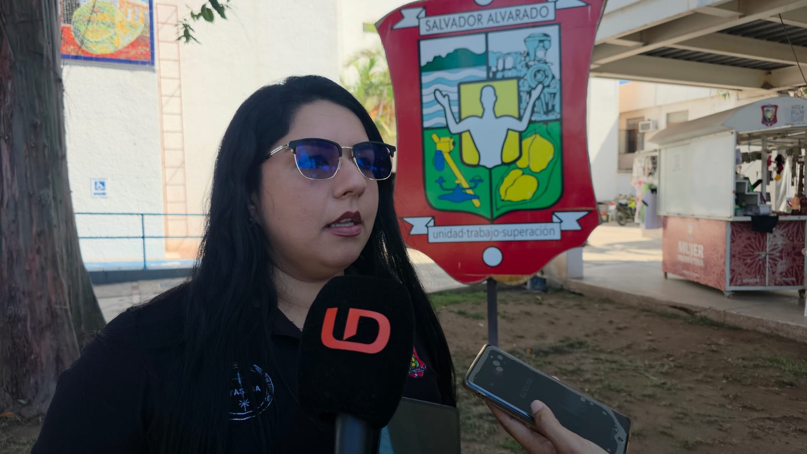 Karina Nohemí López Román con el micrófono de Línea Directa y el logo del Ayuntamiento de Salvador Alvarado