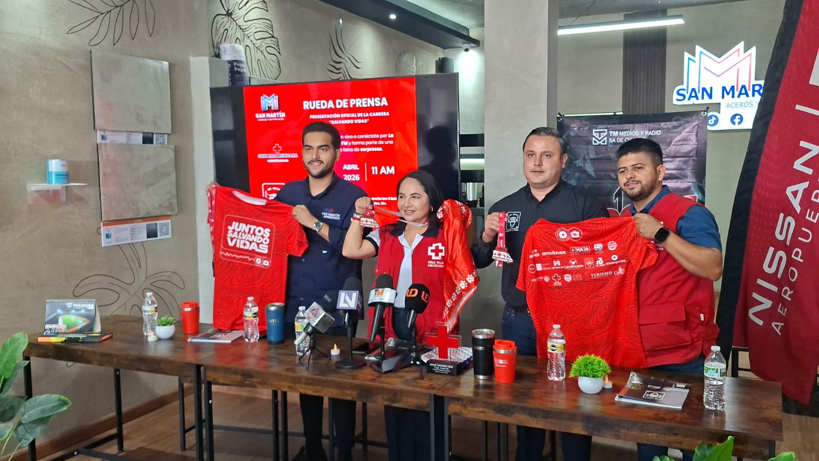 Personas detrás de mesa mostrando camisetas