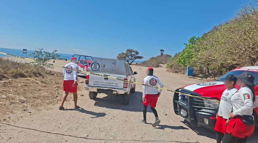 Unidades de corporaciones policiacas y elementos de salvsvidad desplegados en una zona cerca de una playa con una cinta amarilla de precacuón