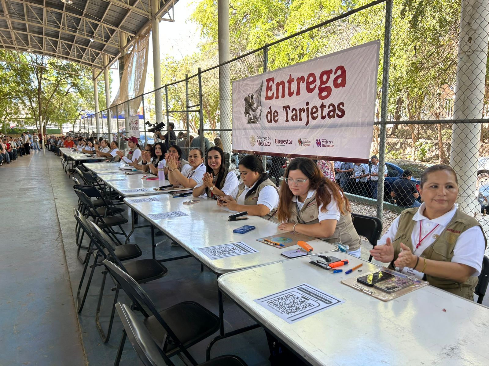 Personas sentadas en una mesa con lona y tarjetas del bienestar
