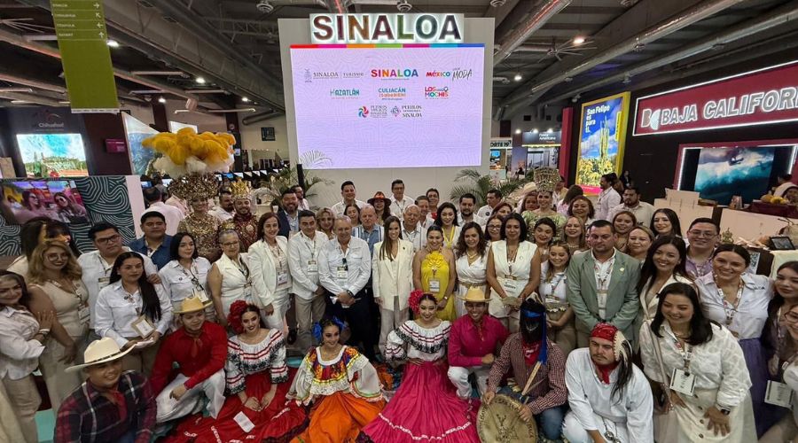 Personas con indumentaria reunida adelante de una pantalla con un letrero de Sinaloa