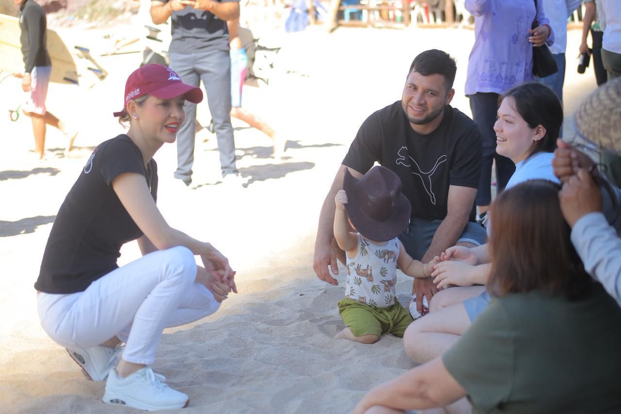 Estrella Palacios incadas junto a turistas en la arena