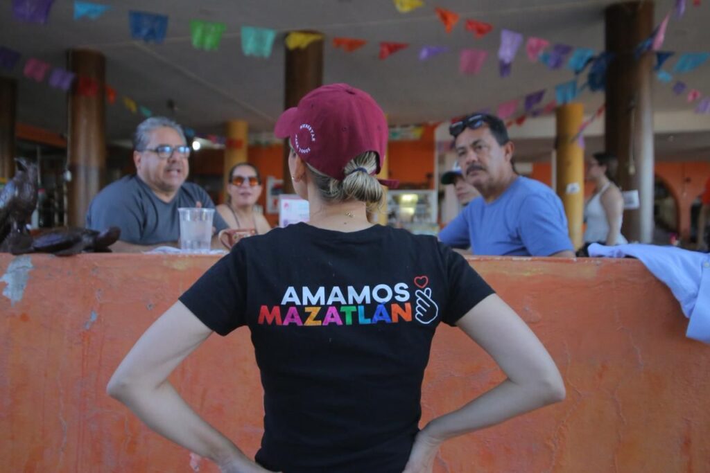 Estrella Palacios con las manos en el cuerpo junto a dos personas en un restaurante