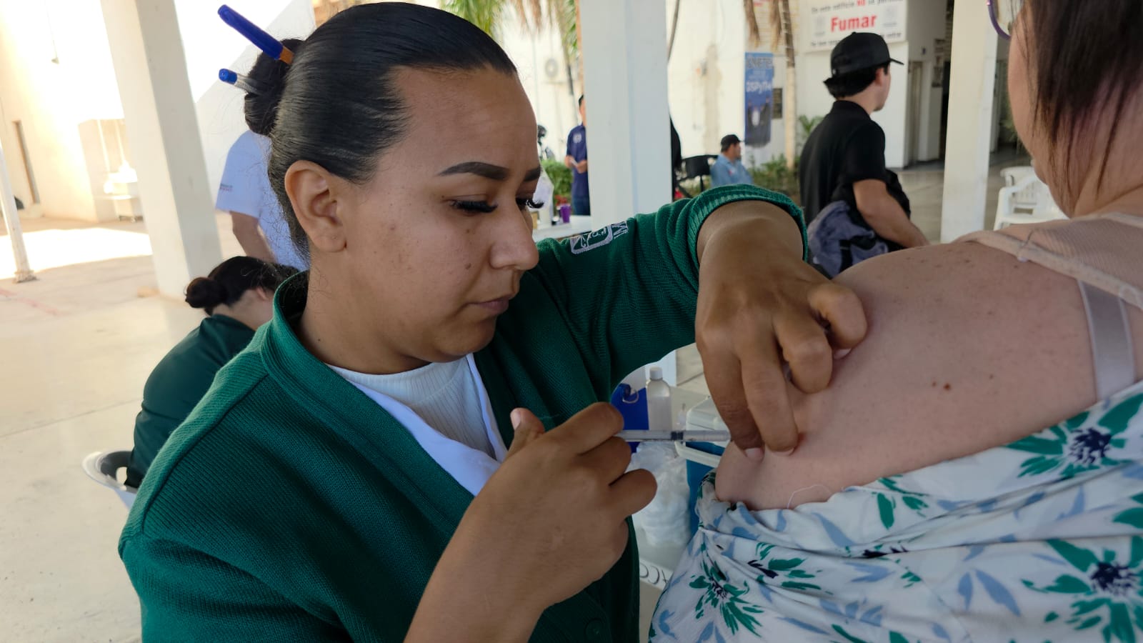 Enfermera aplicando vacuna sobre brazo izquierda a una mujer