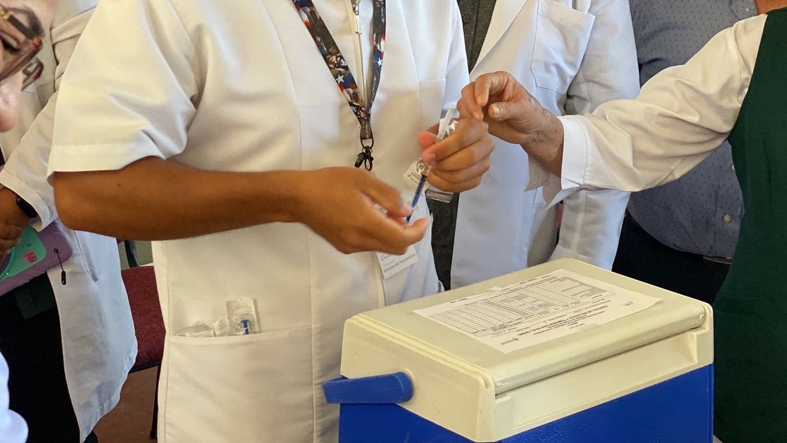 Médico con una vacuna en la mano y una hielera