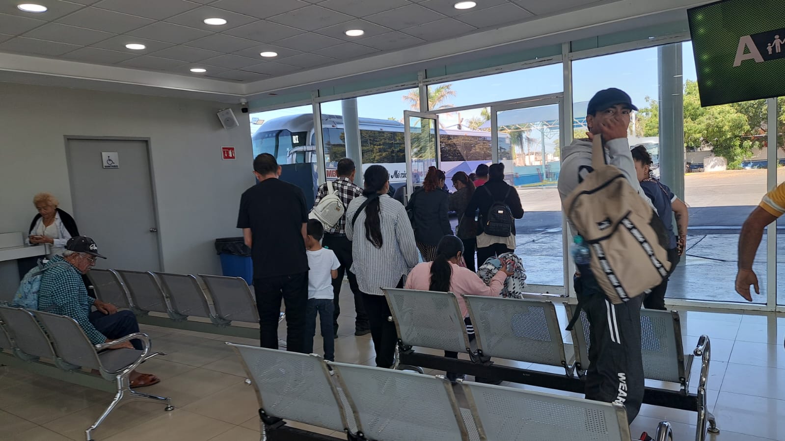 personas en central de autobuses con maletas