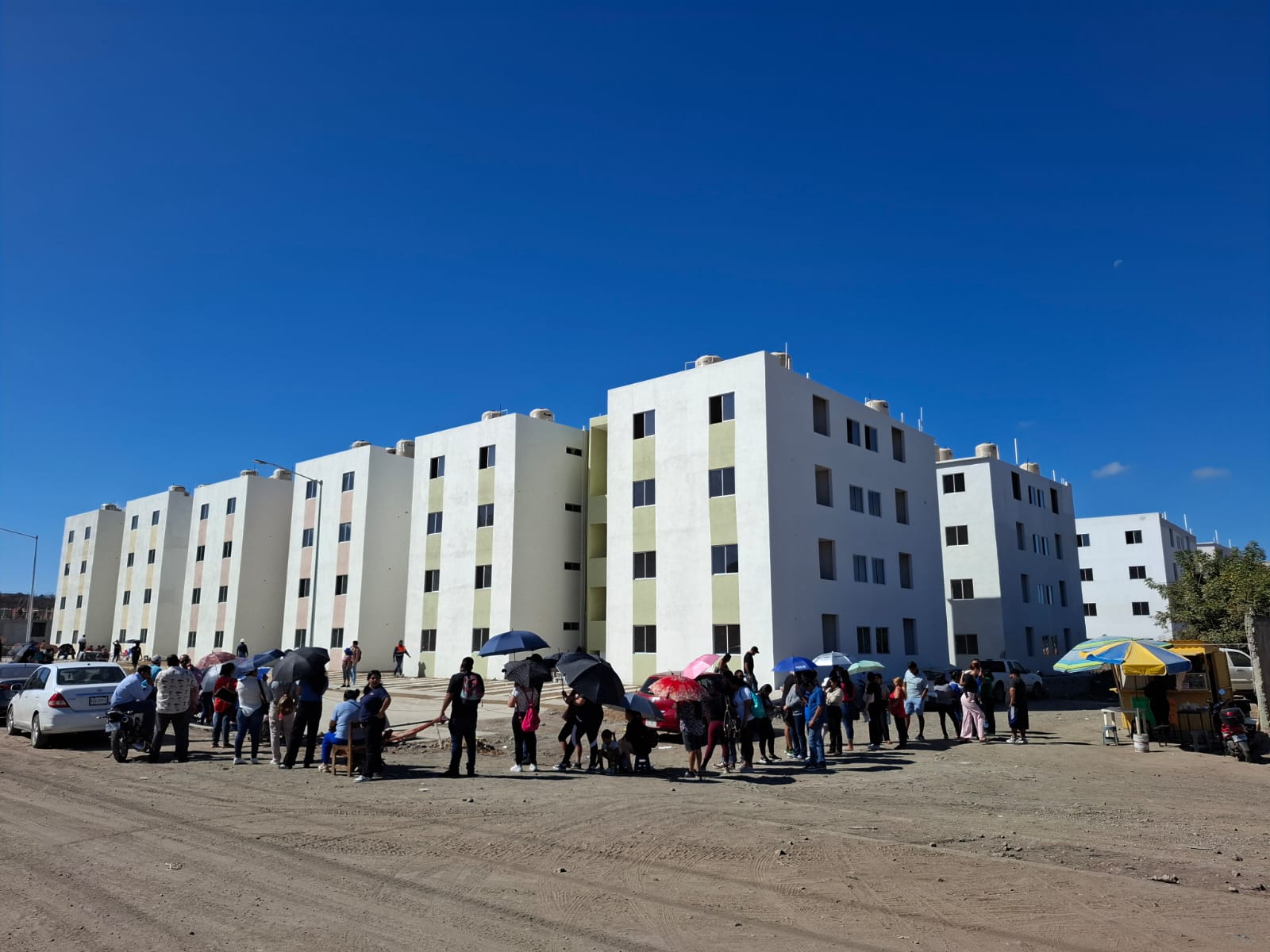 Personas haciendo fila frente a edificios de viviendas del bienestar