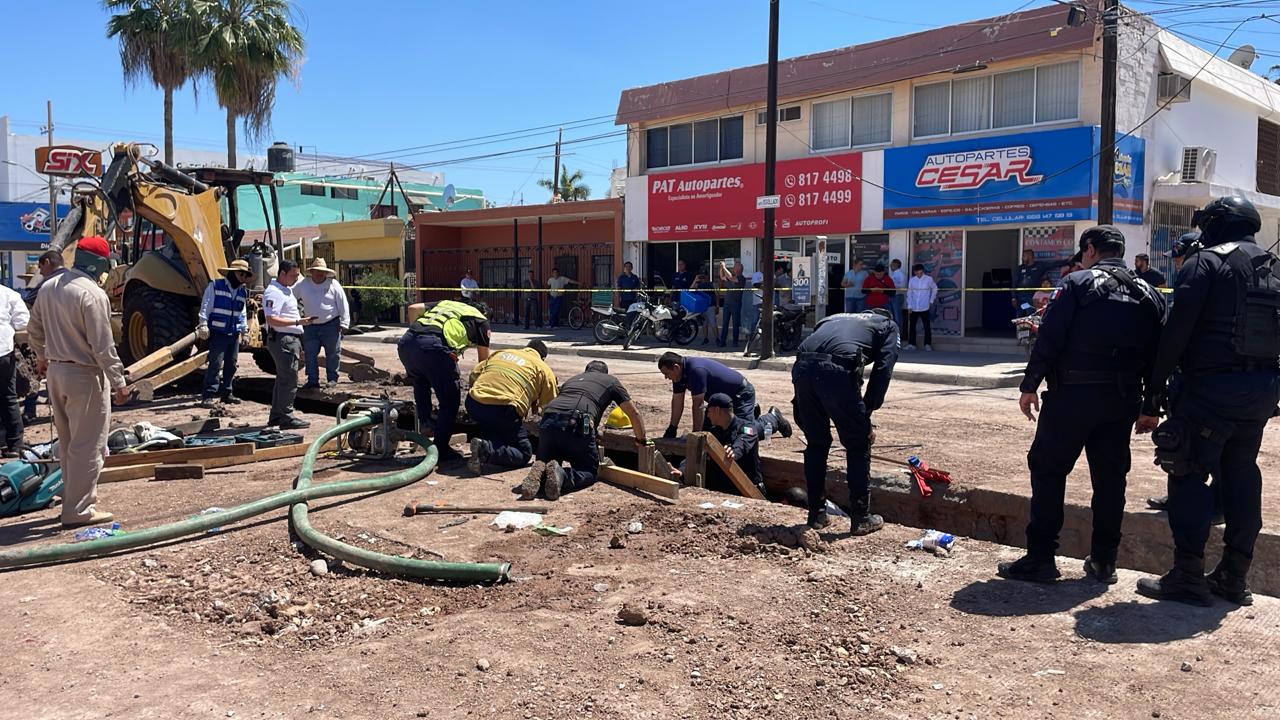Personas en una calle acordonada donde se ve un socabón