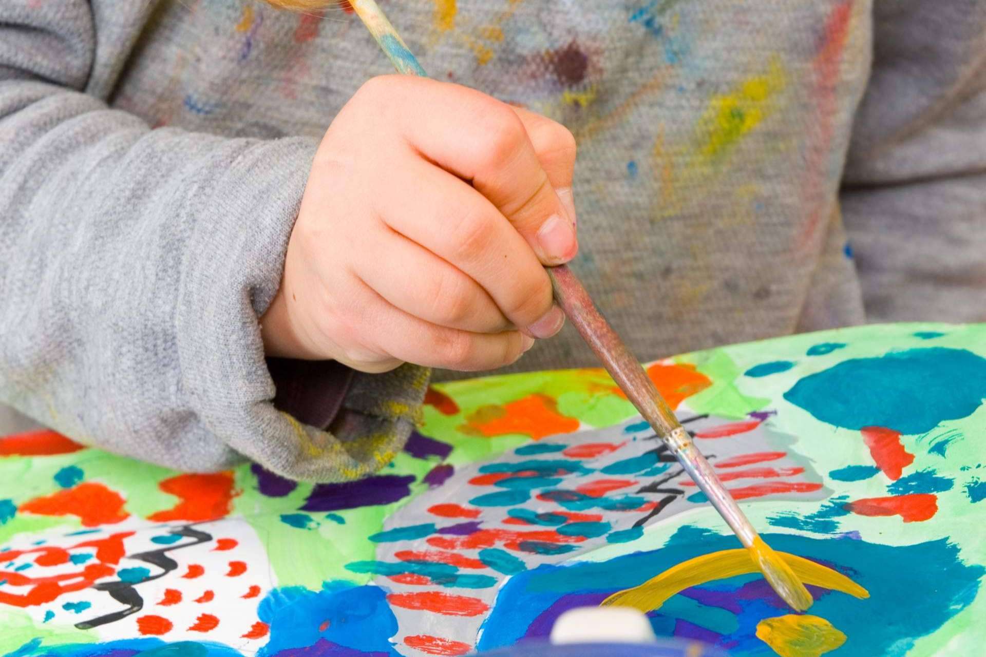 Mano de un niño con un pincel pintando
