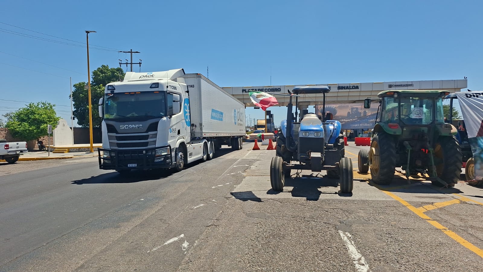Camión de carga y tractores enn una caseta de peaje
