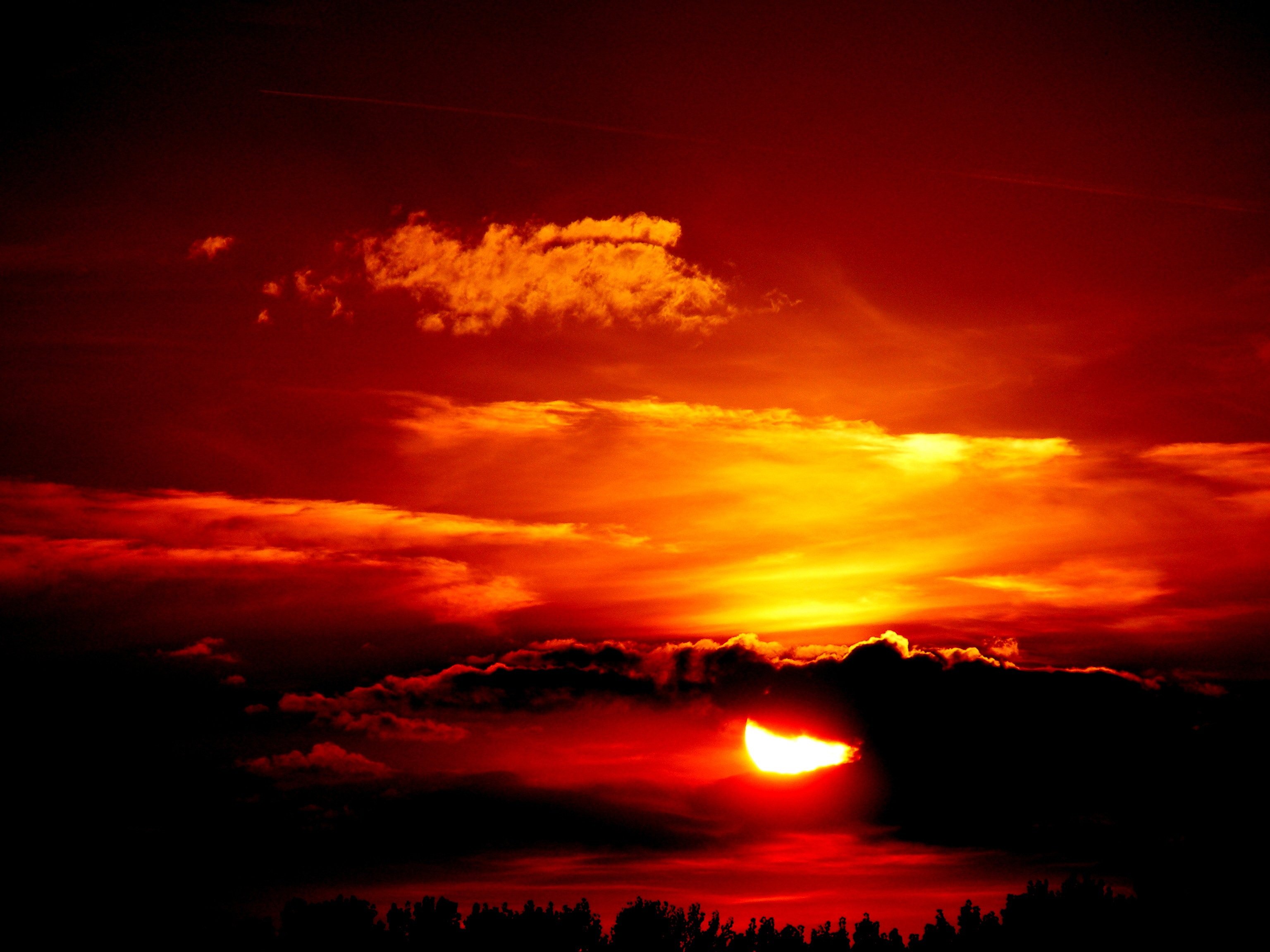 Sol fuerte entre nubes y un cielo naranja
