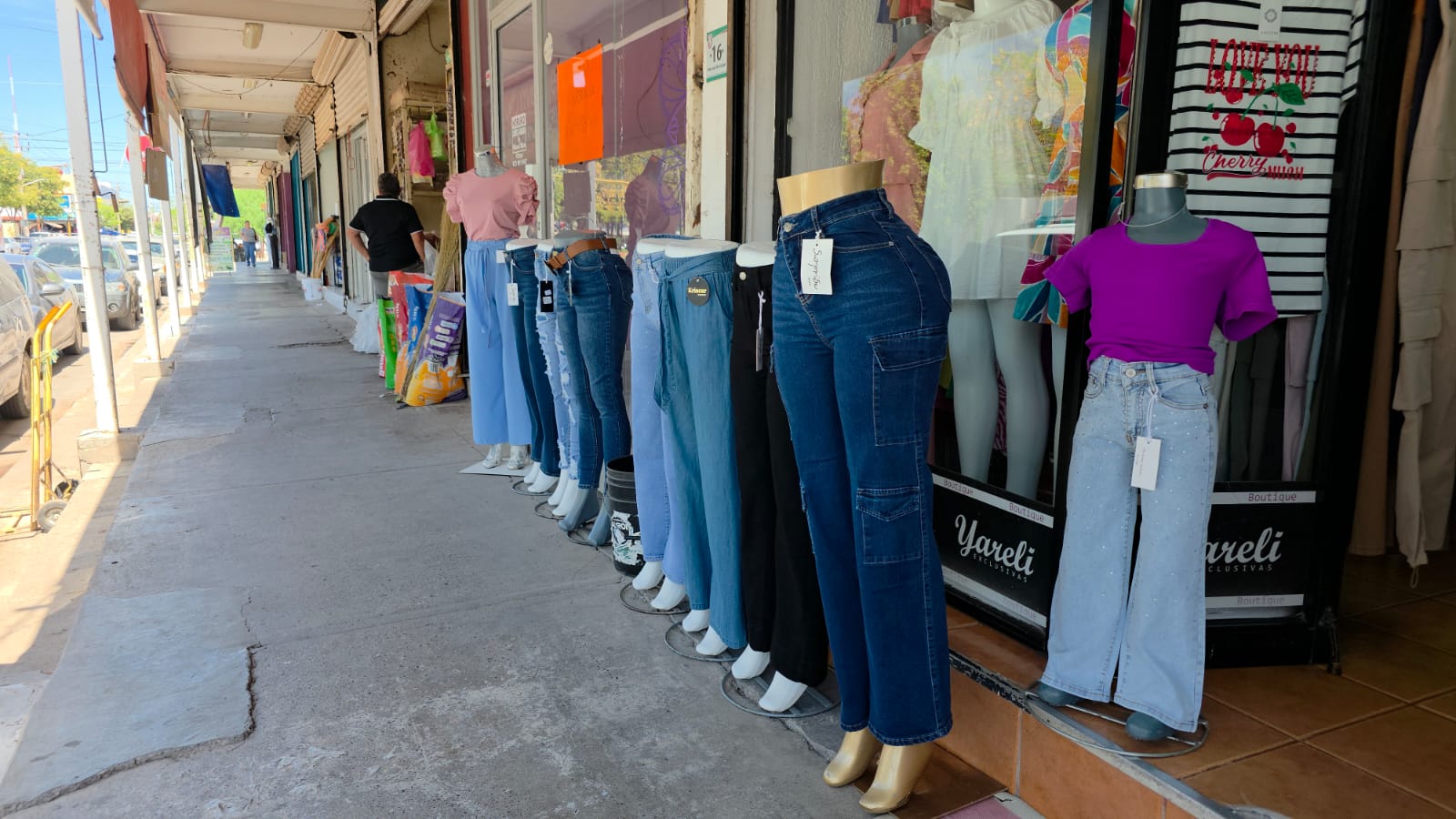 Comercios de ropa con pantalones en maniquís sobre la banqueta