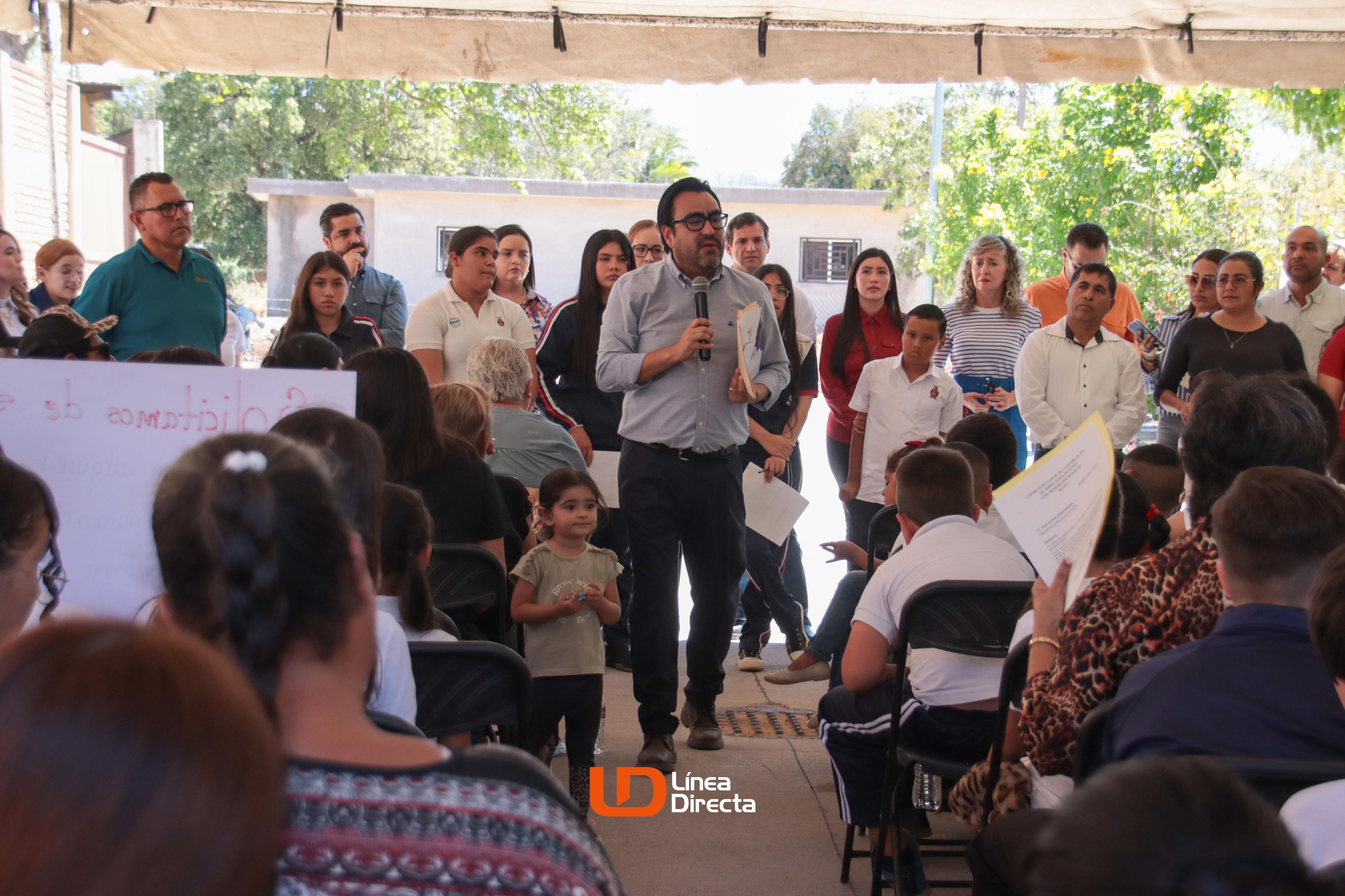 Juan de Dios Gámez Mendívil hablando por micrófono con personas a su alrededor
