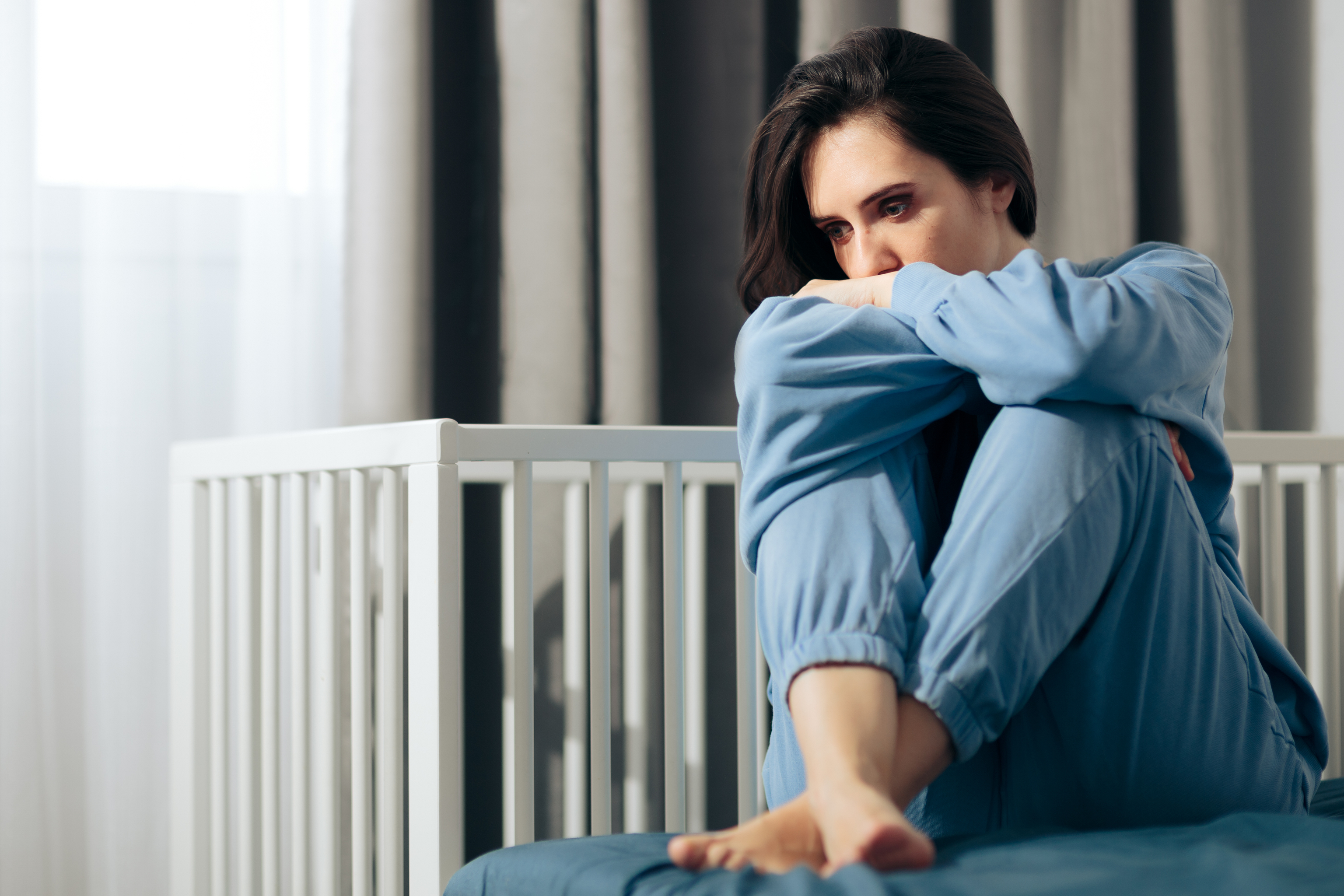 Mujer en posición fetal con la mirada baja