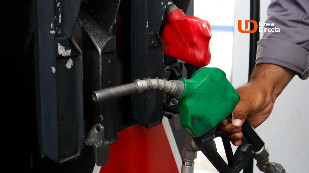 Mano de una persona sosteniendo una manguera de gasolina color verde