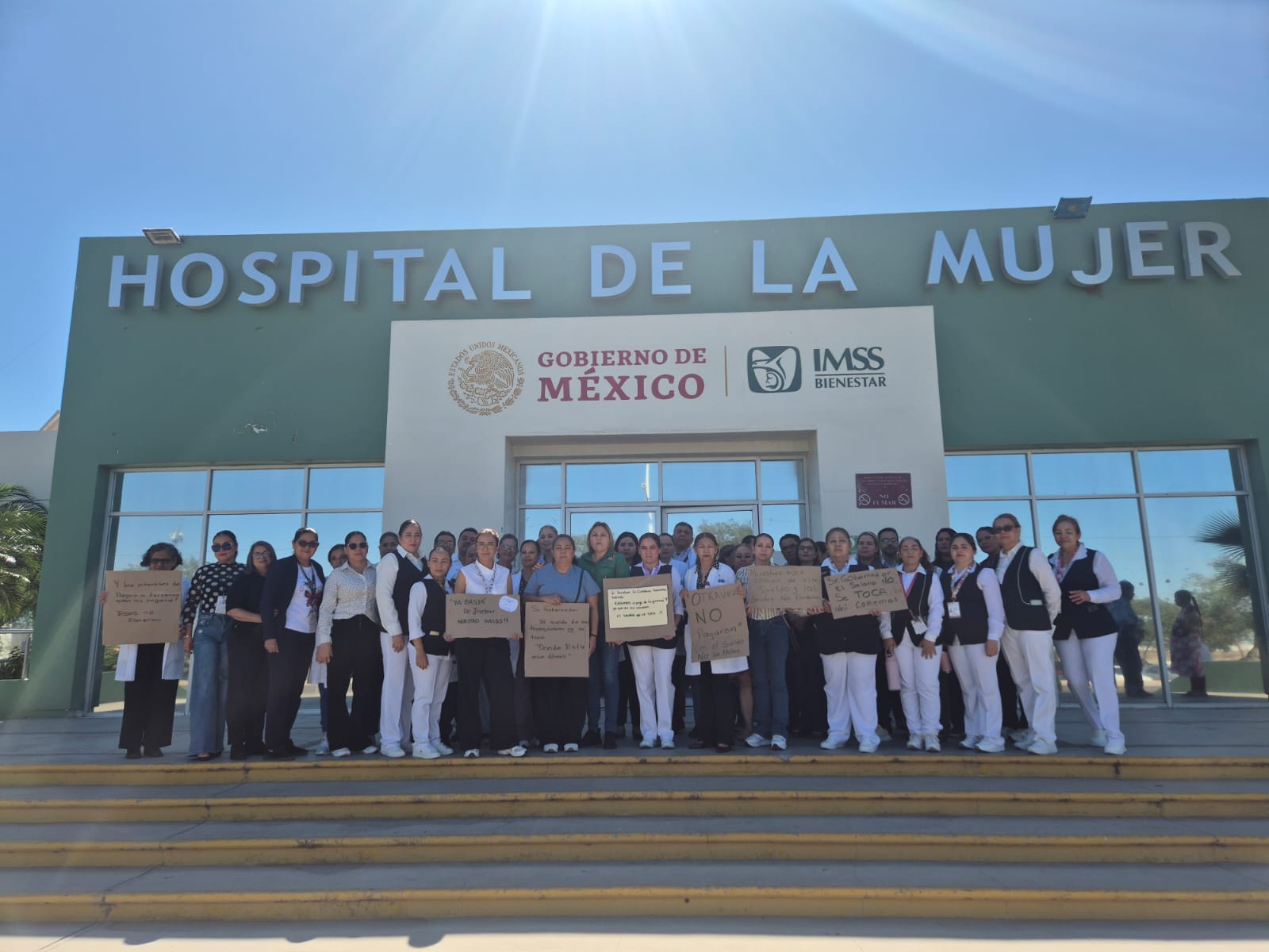 Personas afuera de un hospital con pancartas en una manifestación