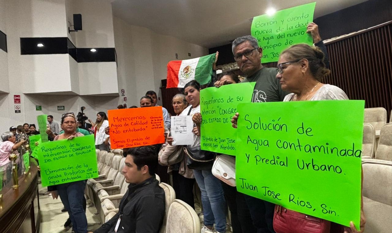 Personas con pancartas de diferentes colores en el Congreso de Sinaloa realizando una protesta