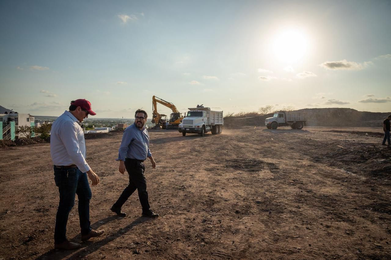 personas en un terreno y al fondo máquinas de construcción