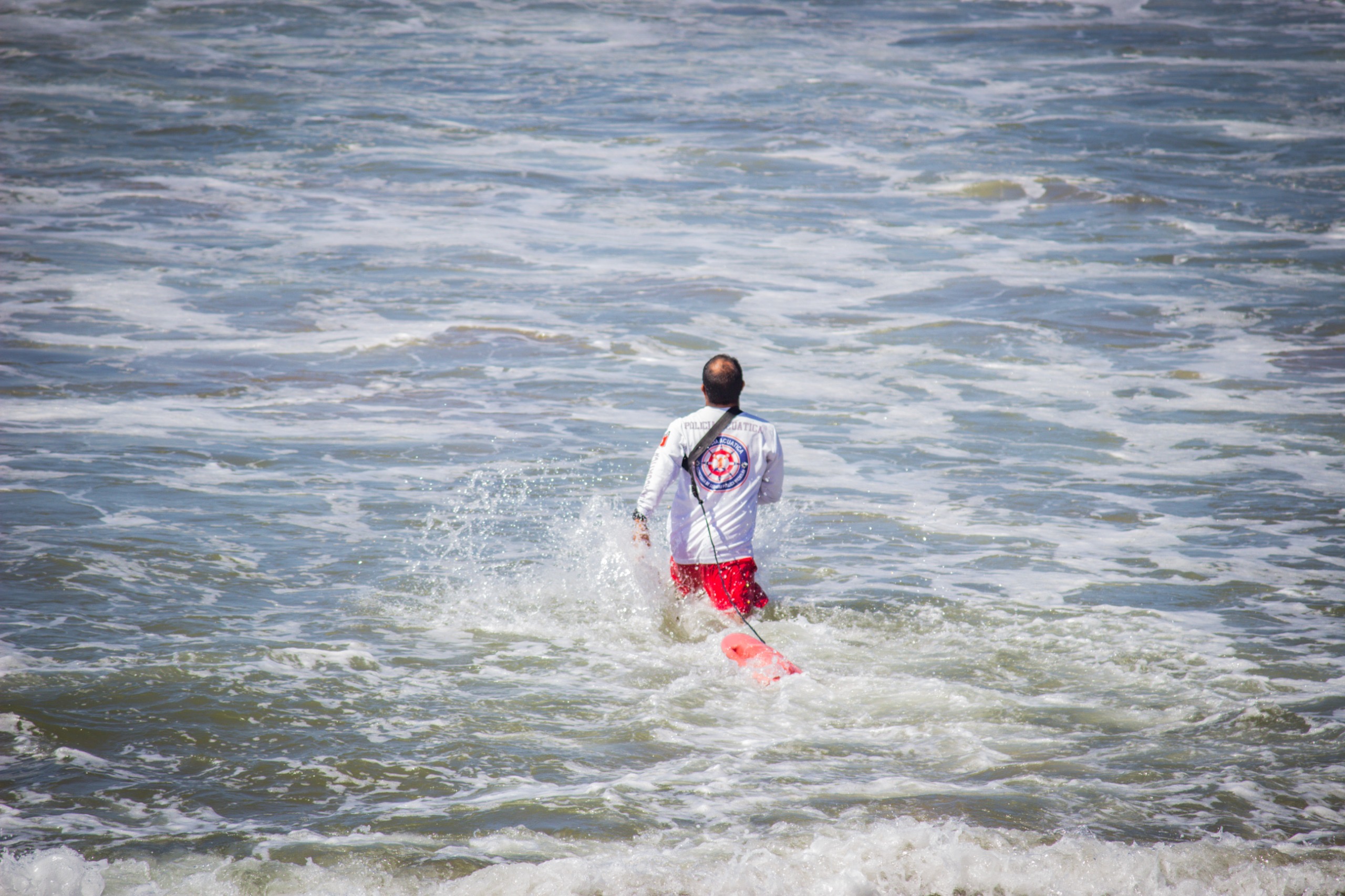 Salvavidas con playera blanca y short rojo en el mar