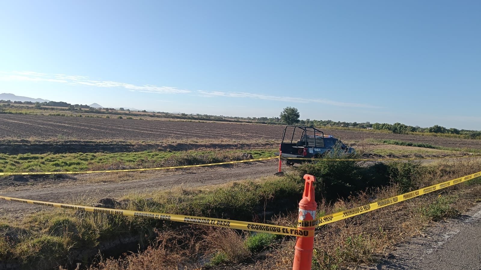 Patrulla estacionada a orillas de campo y cintas amarillas
