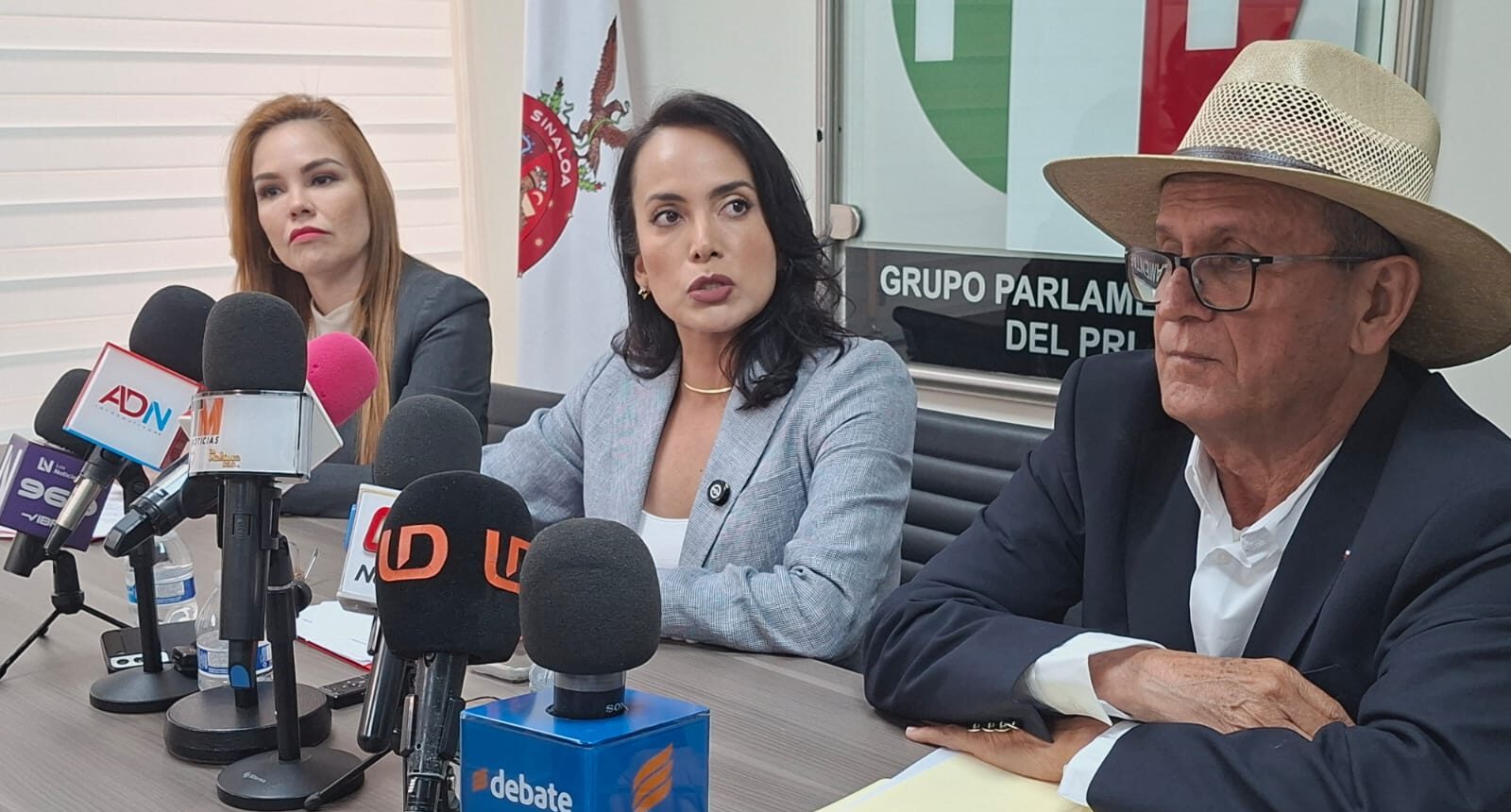 Diputados del PRI con micrófonos de la prensa en una mesa
