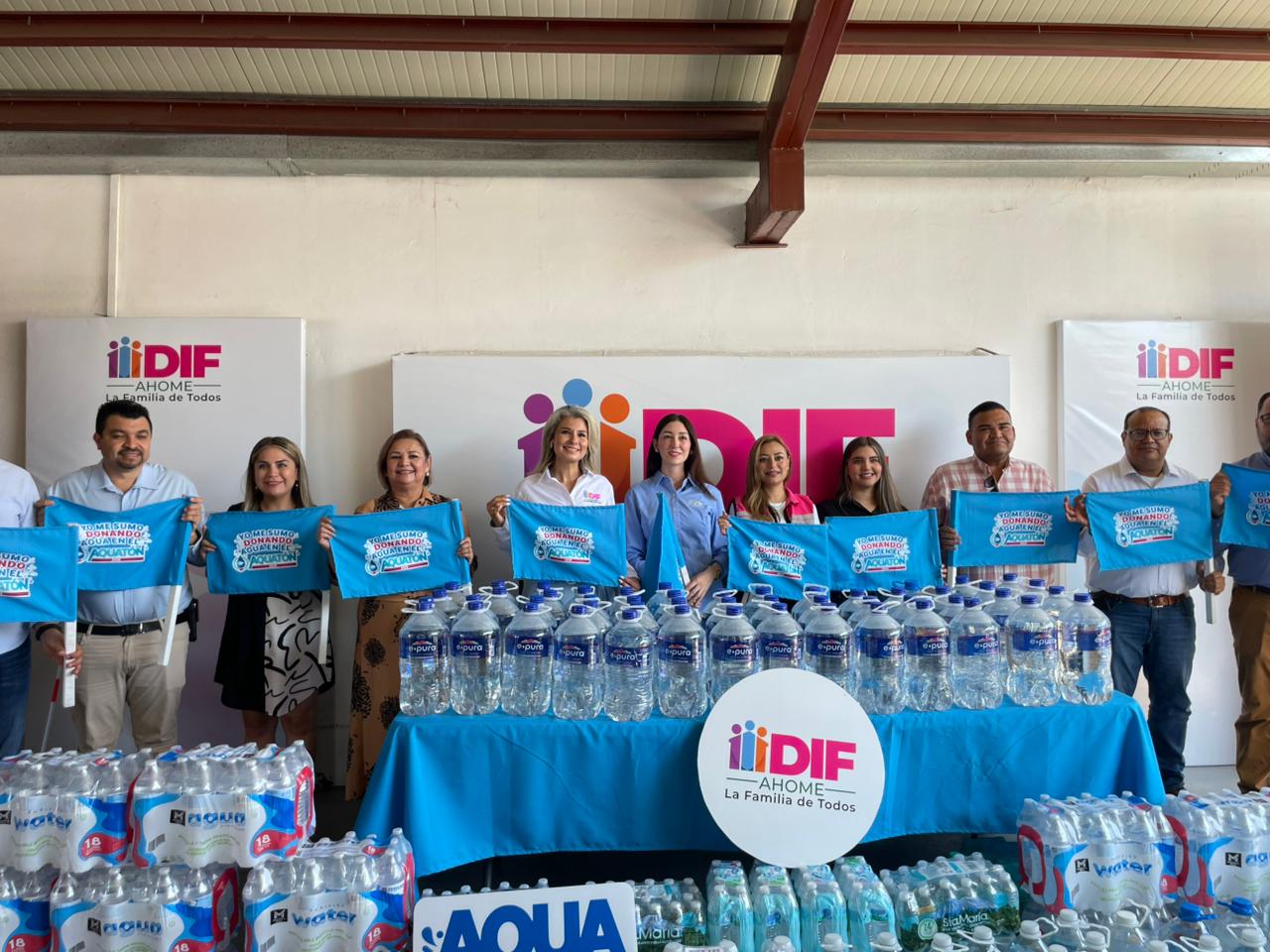 Autoridades de Ahome sosteniendo banderas y alrededor botellas de agua