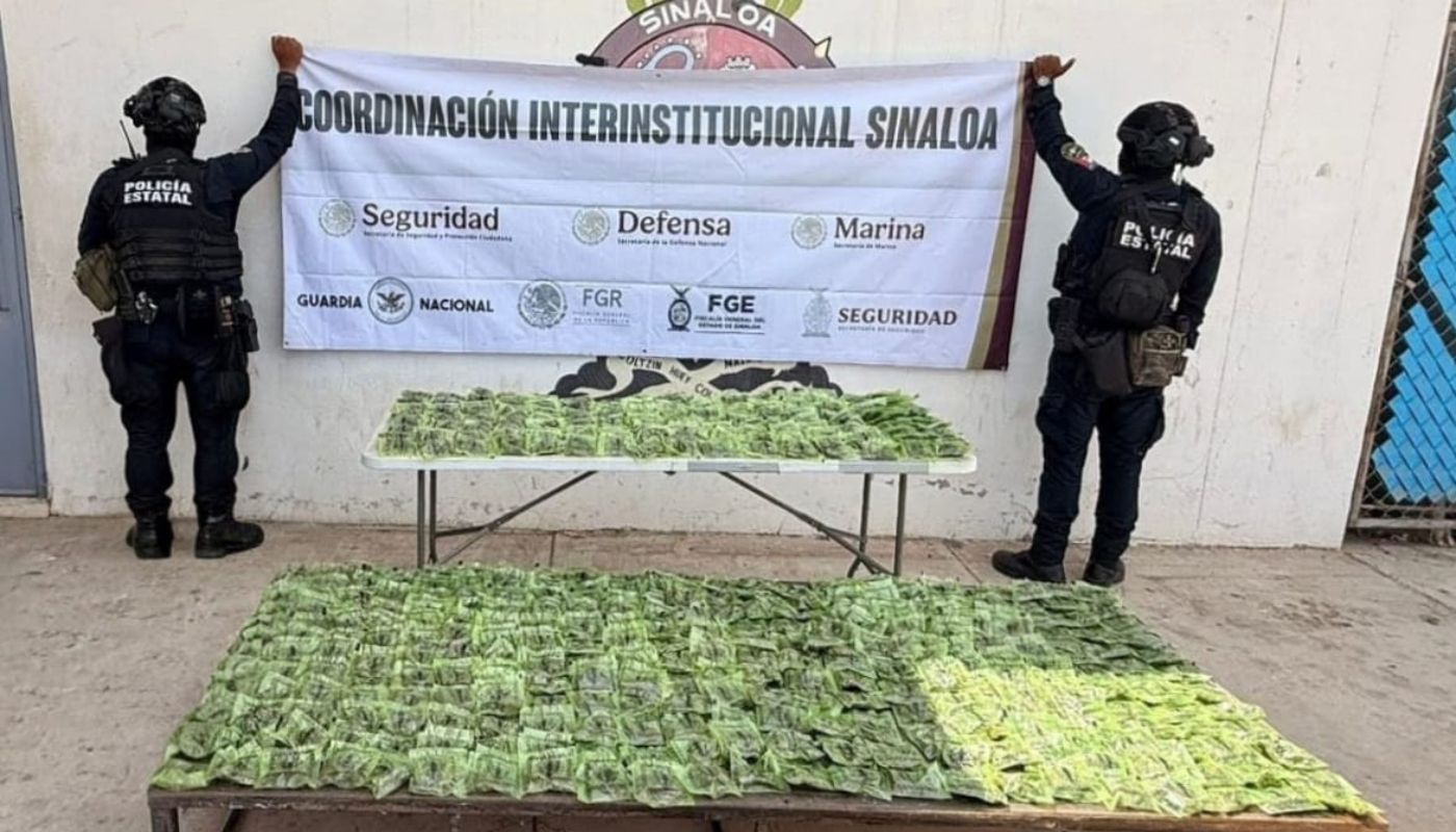 Elementos de seguridad de espaldas y en mesas bolsas de droga