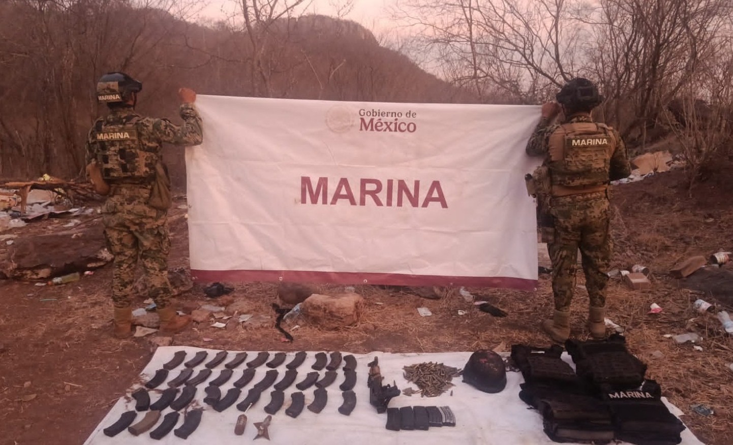 Dos elementos de la Marina con una lona y armas y droga en el piso