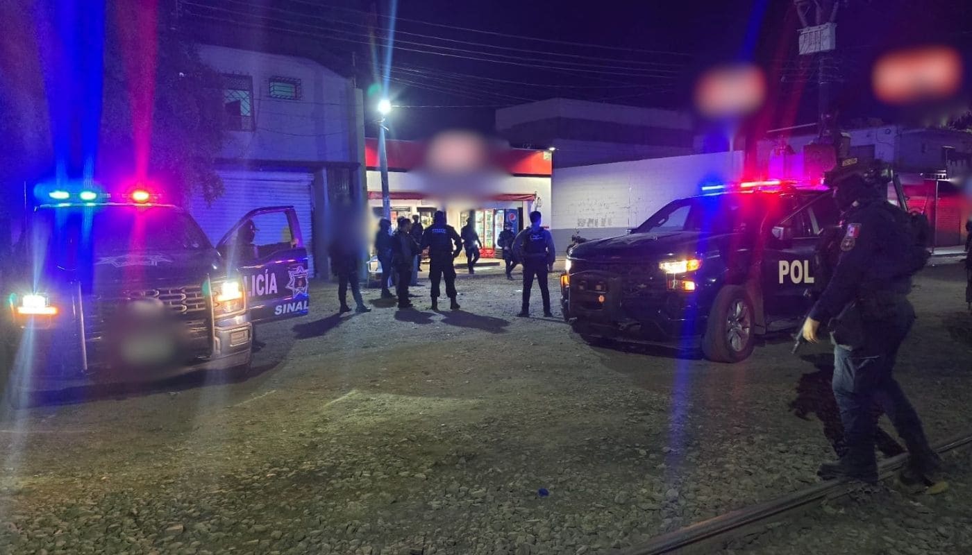 Dos camionetas de la policía estatal con las sirenas encendidas junto a elementos de seguridad frente a un expendio