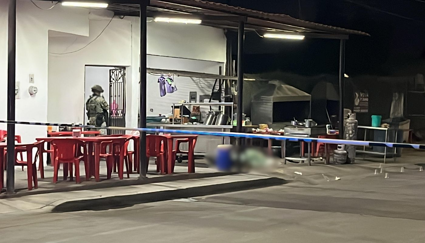 Carreta de tacos con sillas rojas junto a un elemento del ejercito mexicano
