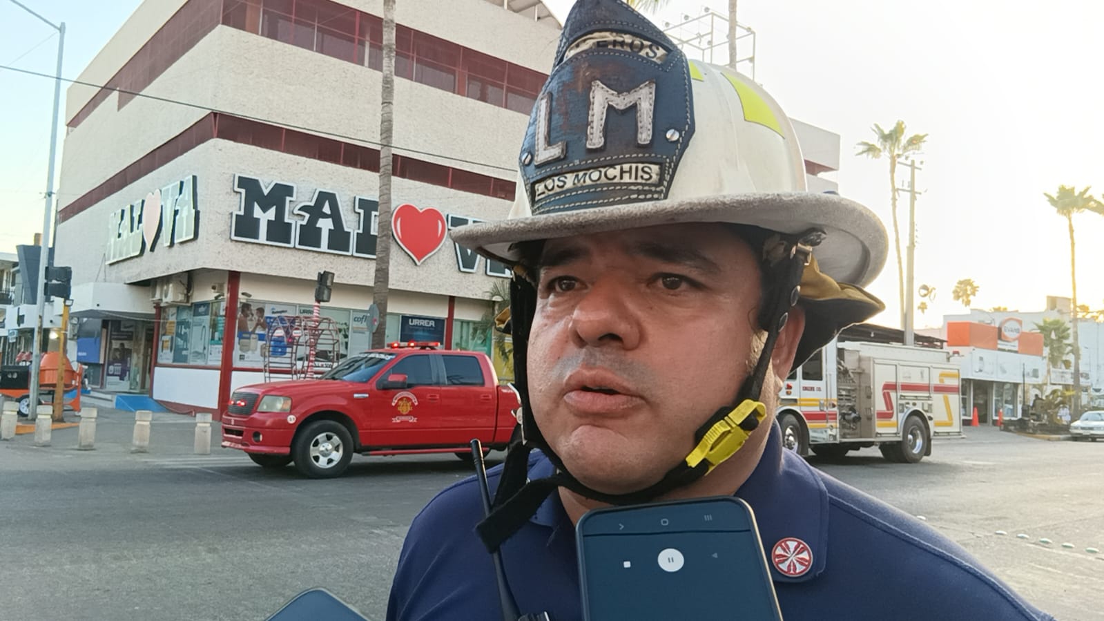 Bombero hablando a teléfono frente a edifico de ferretería
