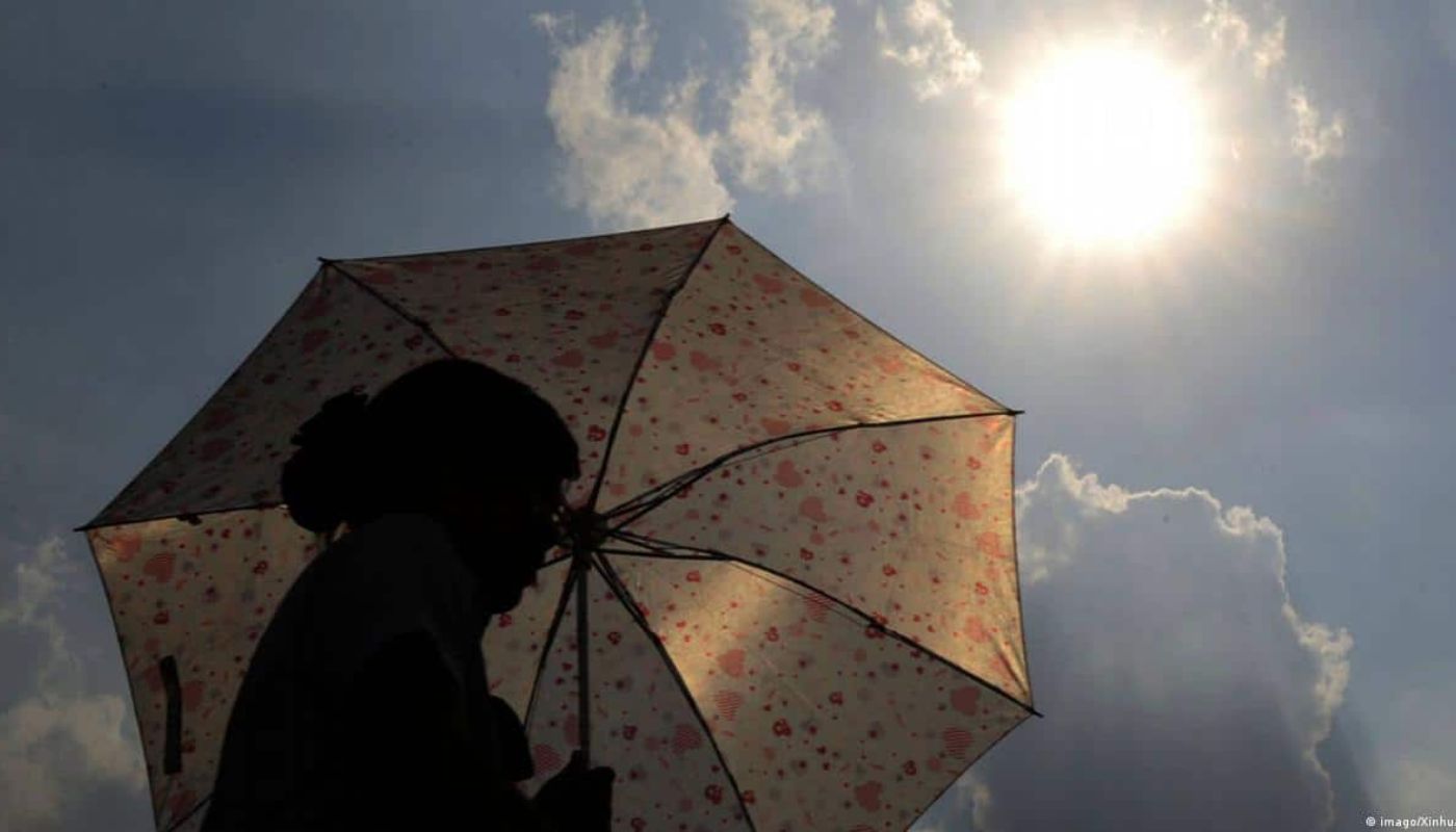 Mujer con una sombrilla y sol en un punto alto