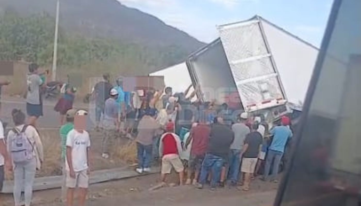 Personas saqueando mercancía de un tráiler descompuesto en una carretera