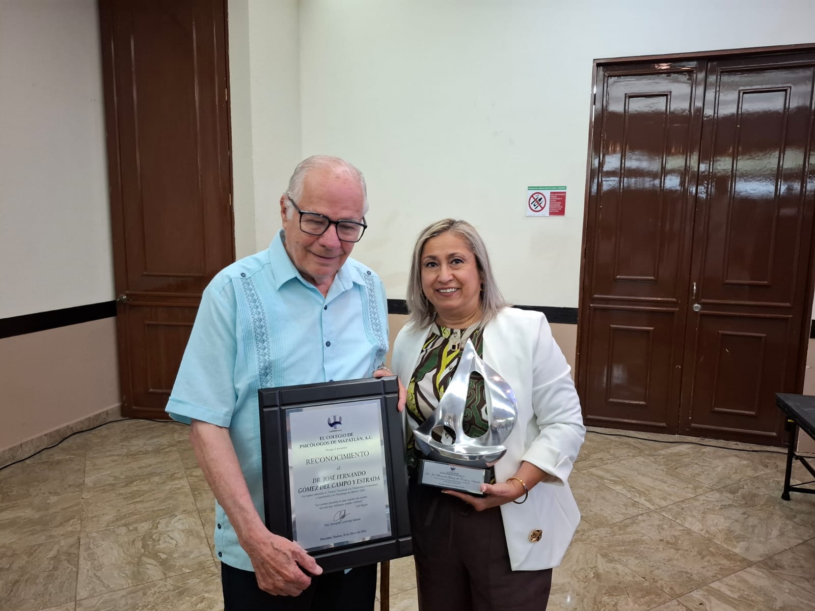 Georgina Lizárraga Salazar, presidenta del Colegio de Psicólogos de Mazatlán junto a un reconocimiento