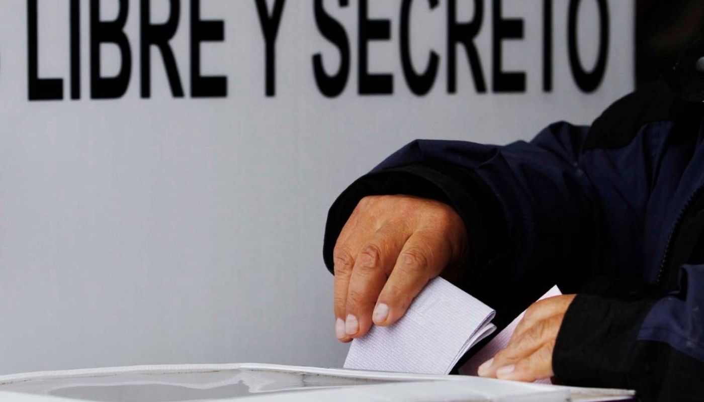 Persona depositando papel dentro de casilla electoral