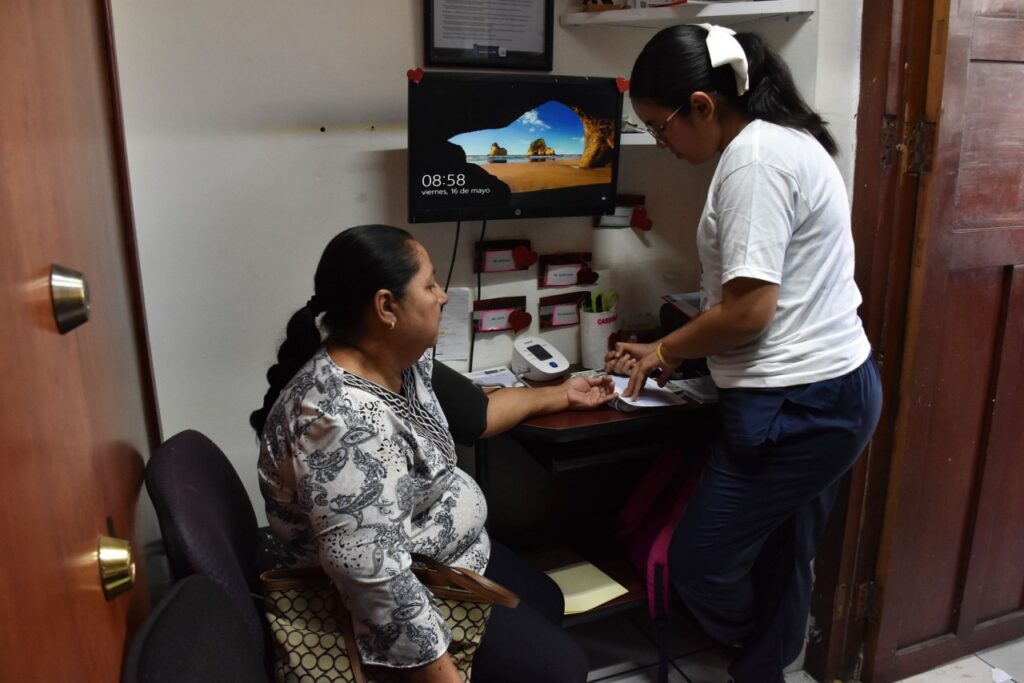 Persona mayor sentada junto a personal médico en consulta