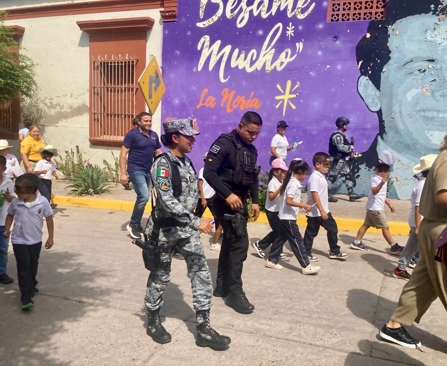 Un elementos de la Guardia Nacional junto a policía y niños de escuela