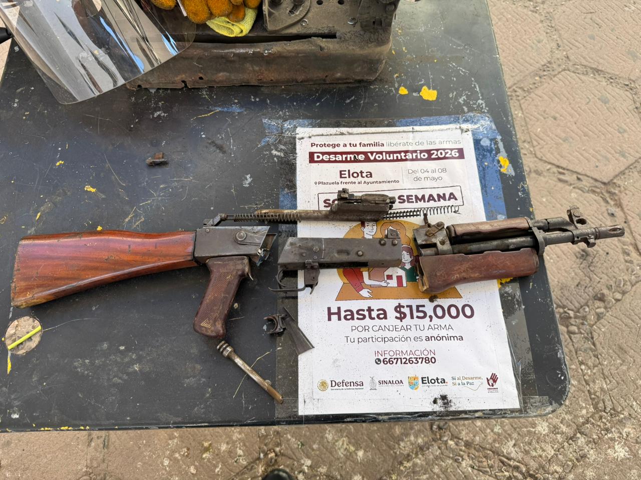 arma larga destruida con cartel informativo de desarme voluntario debajo