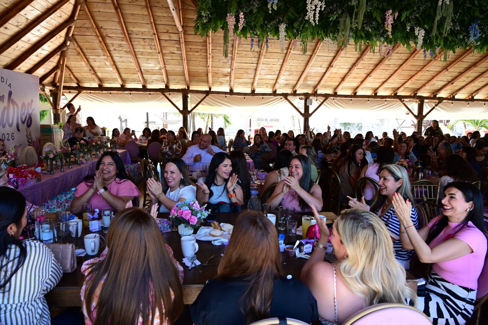 Mujeres sentadas en sillas y mesas con mampara del día de las madres