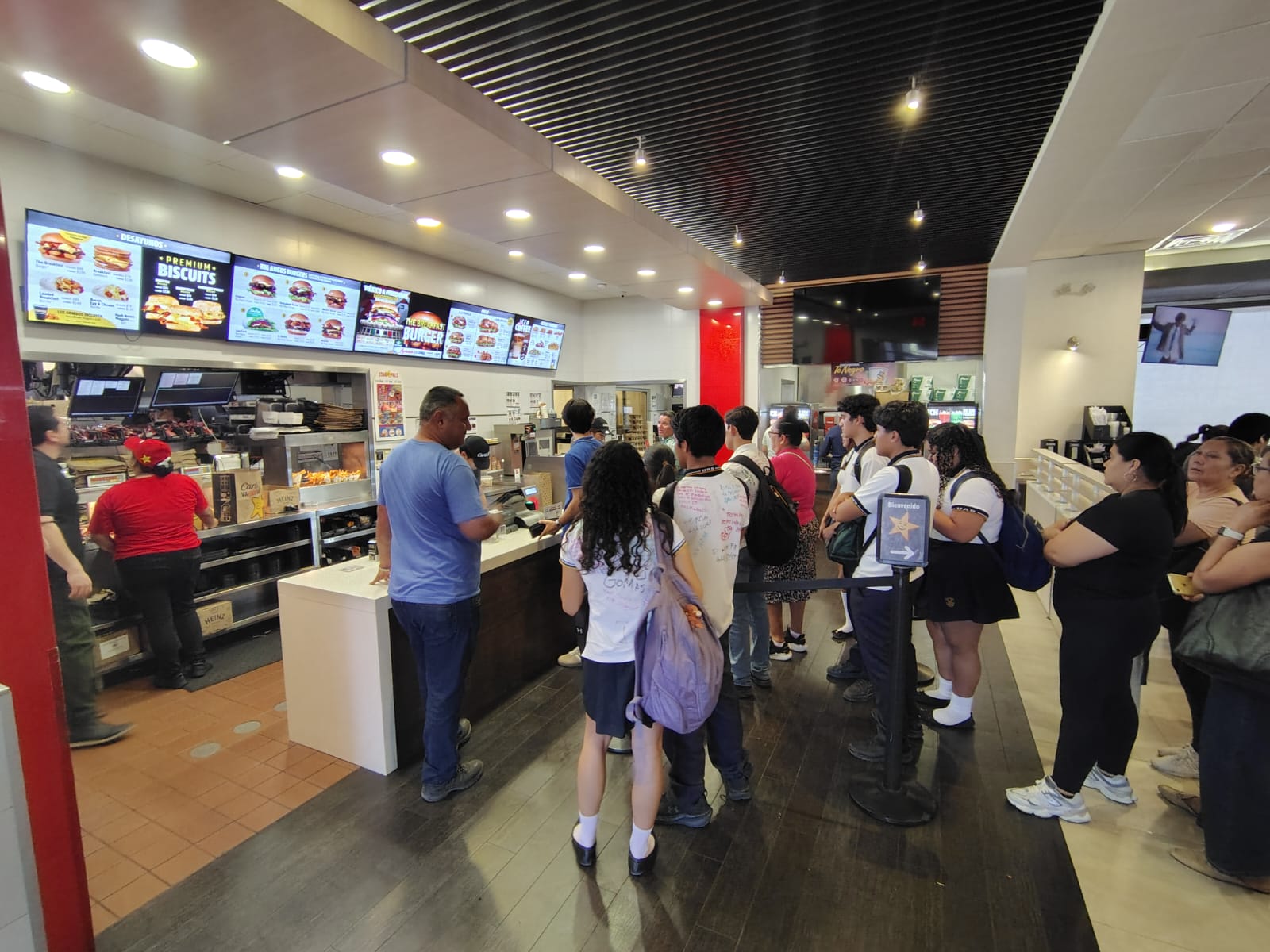 Personas haciendo fila en establecimiento de hamburguesas