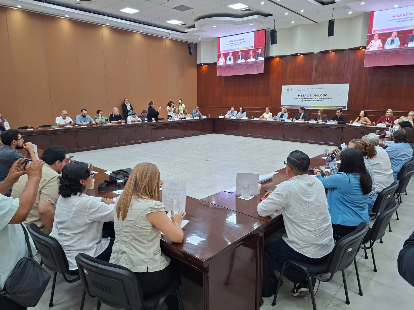 Diputados en reunión con proyecciones y mesas