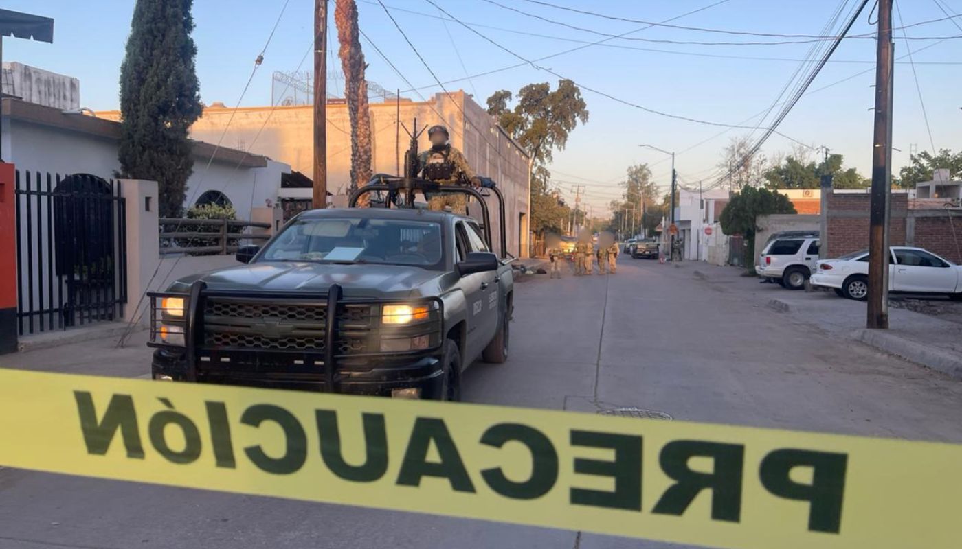 Unidad policiaca en una calle entre casas con una cinta amarilla