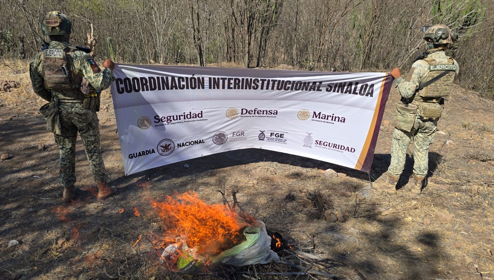Elementos del ejercito mexicano con pancarta y fuego en el suelo