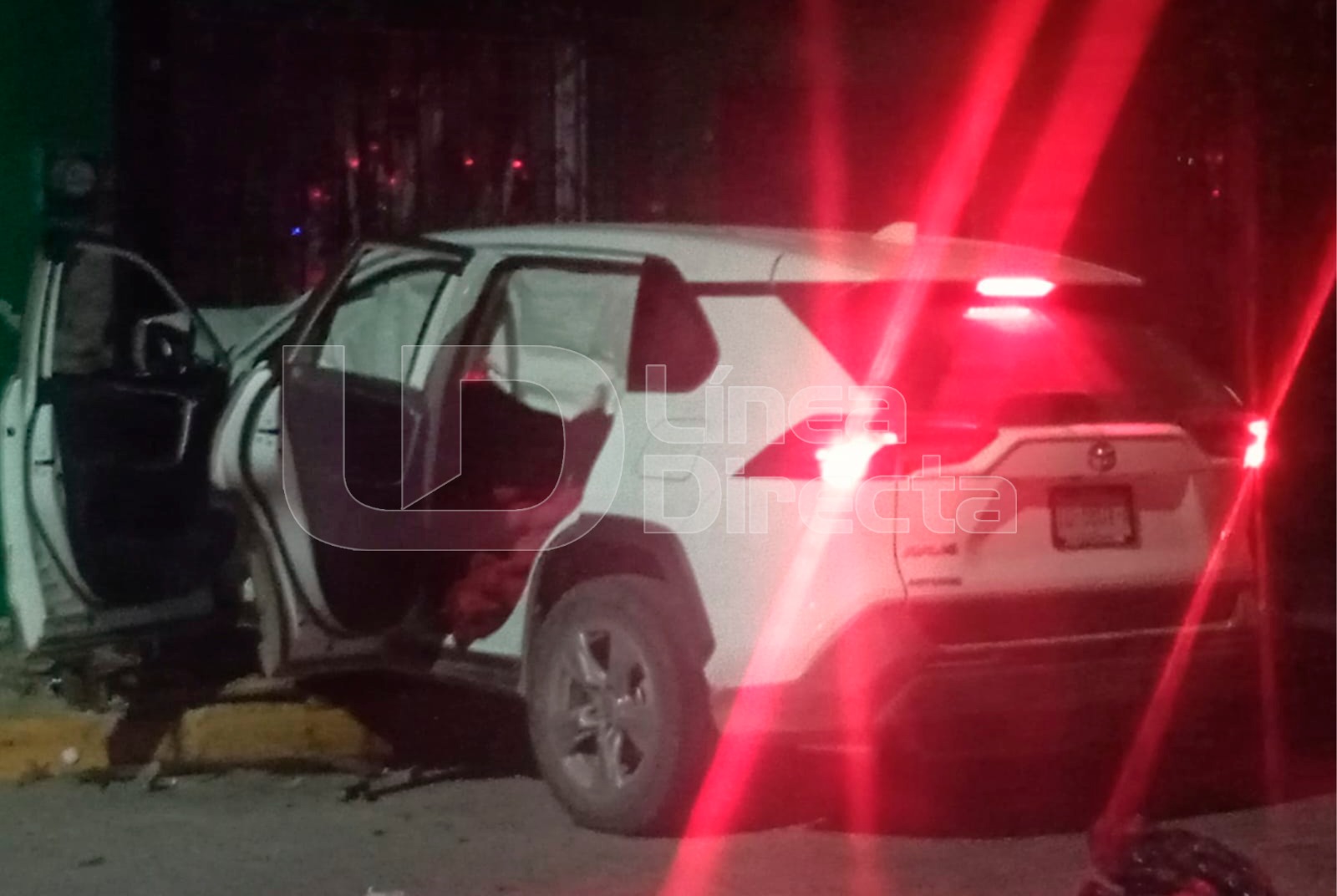 Camioneta de color blanco con las puertas abiertas y luces encendidas impactada en un poste de luz